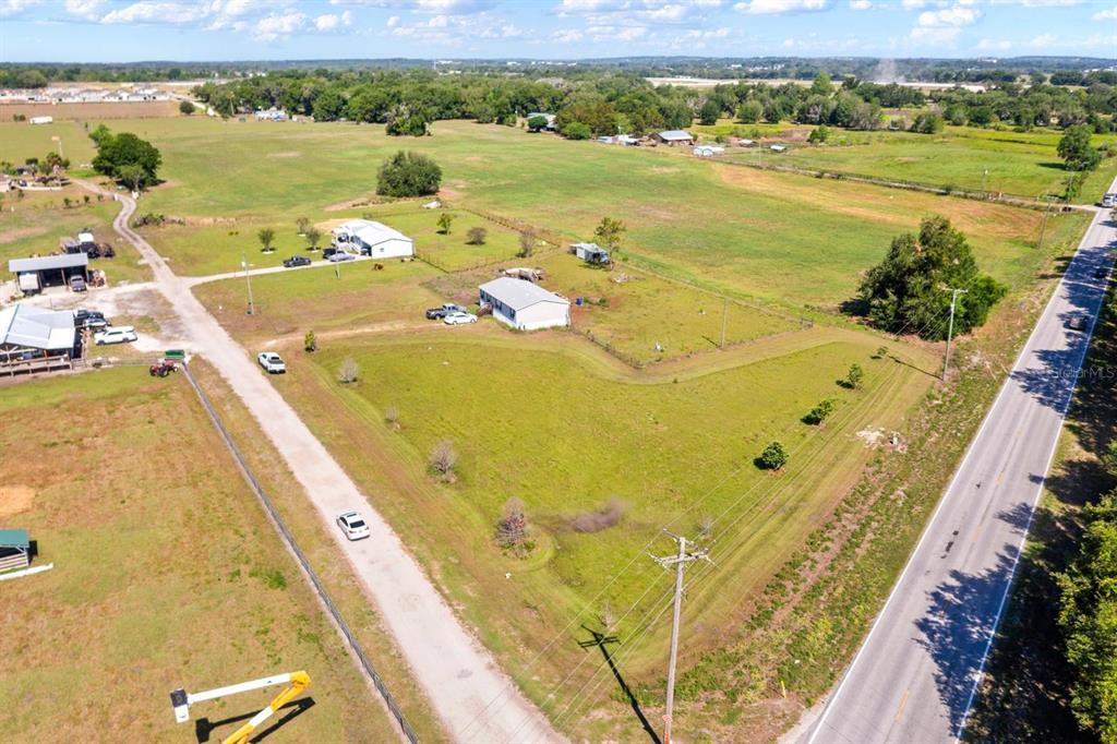 An aerial view shows a rural property with two houses, open fields, and a paved road — 12011 OLD LAKELAND HIGHWAY, DADE CITY, FL