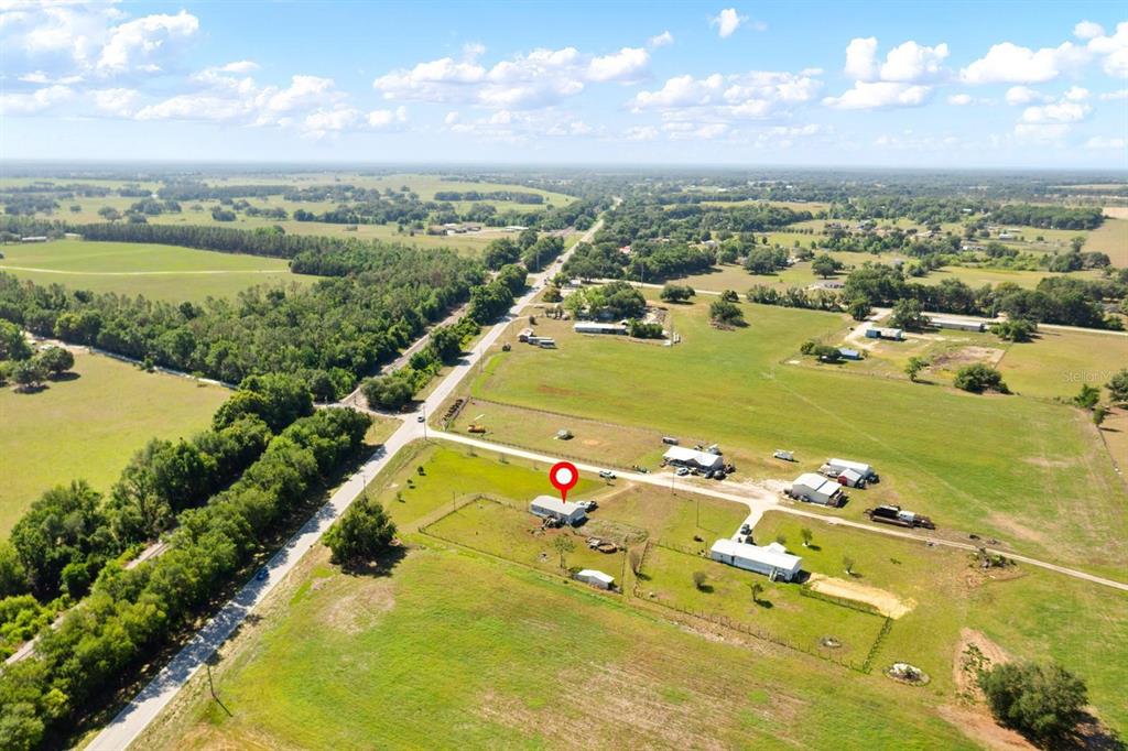 An aerial view shows a rural property with a house, outbuildings, and surrounding pasture land — 12011 OLD LAKELAND HIGHWAY, DADE CITY, FL