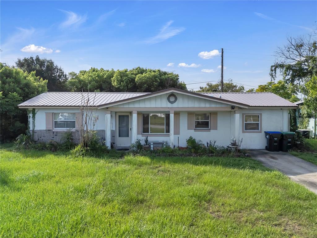 A single-story house with a metal roof, light-colored exterior, and a front lawn — 6201 ANTILLA DRIVE, ORLANDO, FL