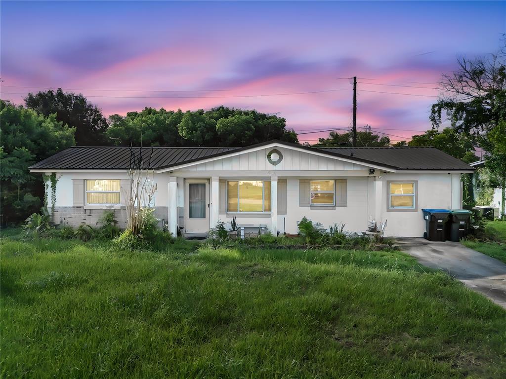 A single-story house with a metal roof and a large, overgrown front lawn — 6201 ANTILLA DRIVE, ORLANDO, FL