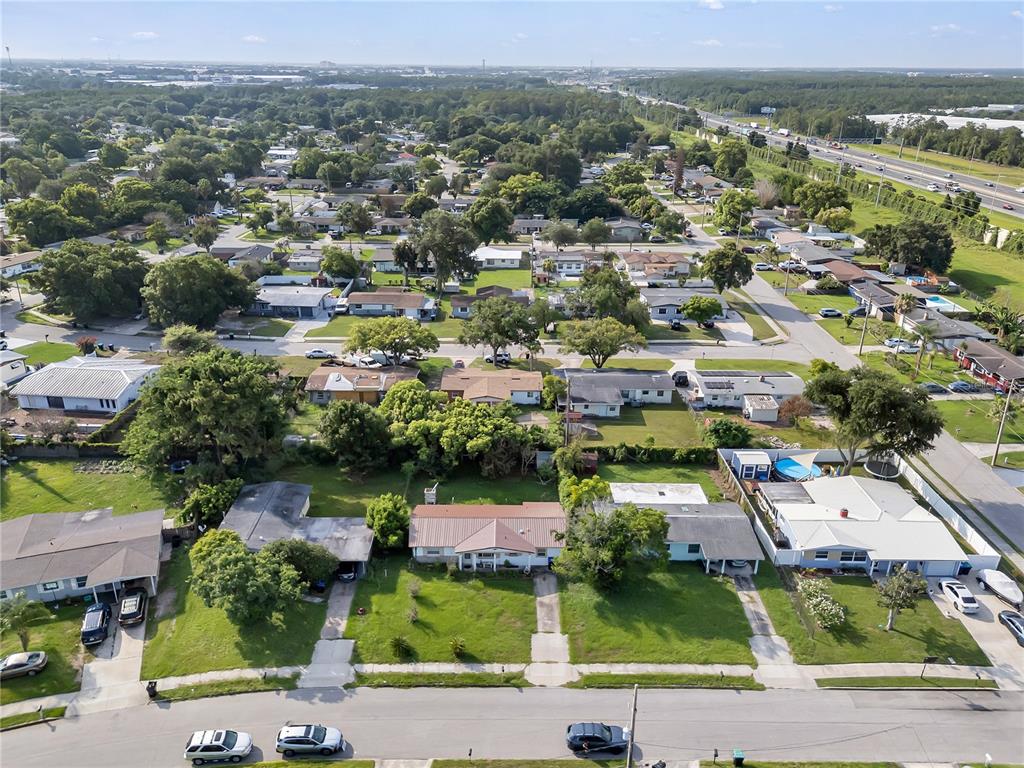 An aerial view shows a suburban neighborhood with single-story houses, green lawns, and nearby highways — 6201 ANTILLA DRIVE, ORLANDO, FL
