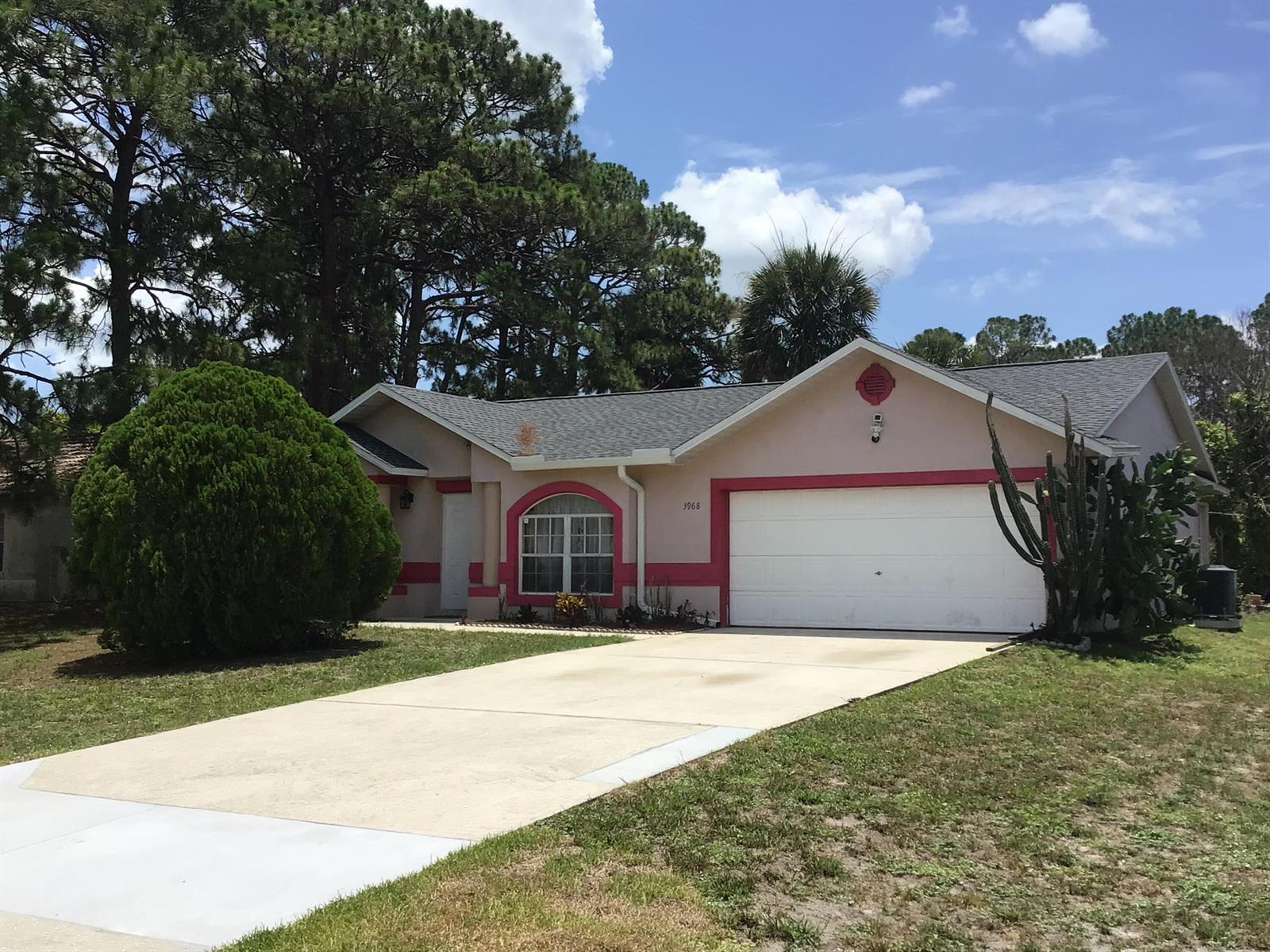 A single-story house with a white garage door, pink trim, and a large front bush — 3968 Jupiter Boulevard SE, Palm Bay FL 32909, PALM BAY, FL