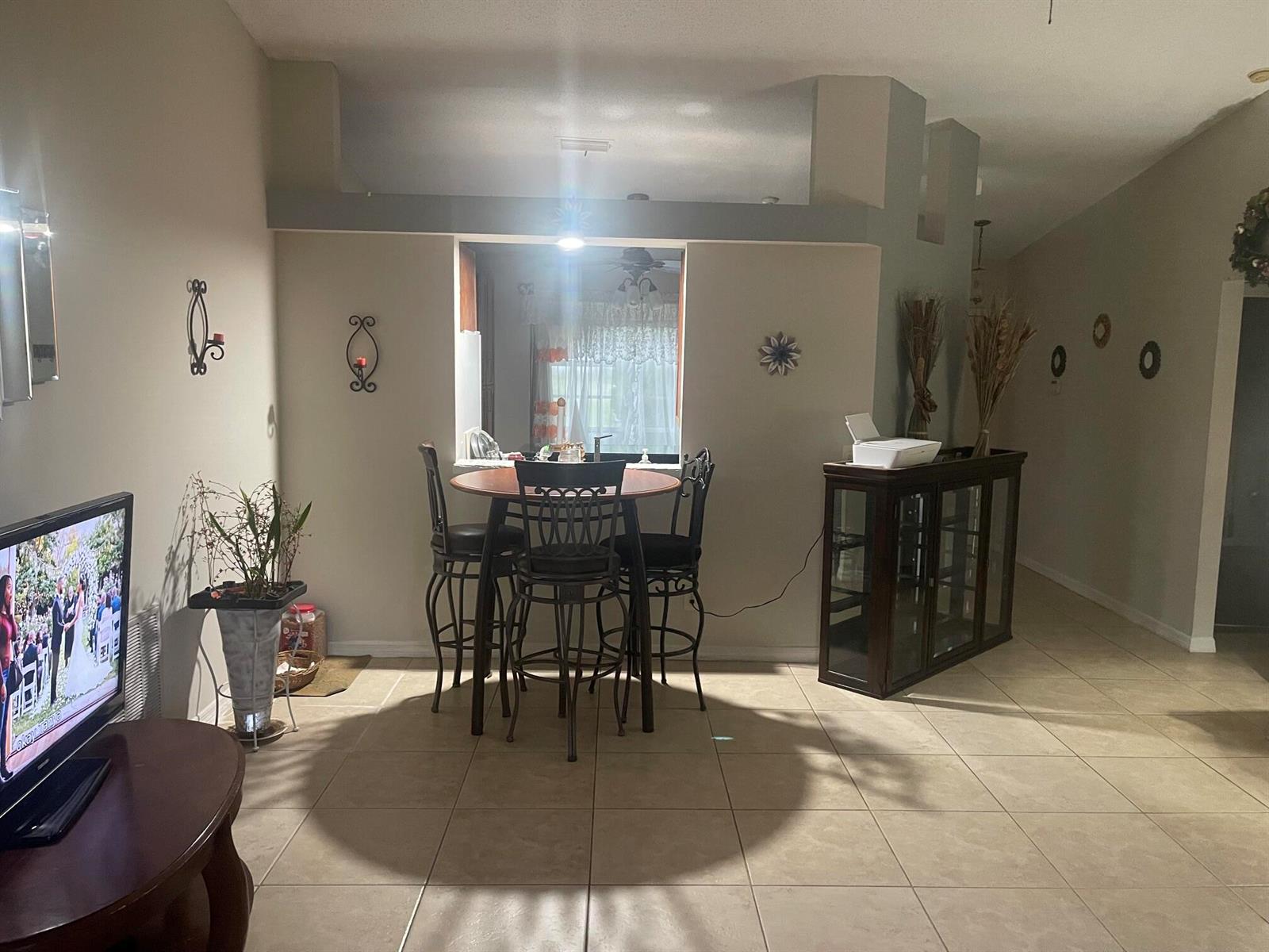 A dining area with a round table and stools sits in front of a kitchen pass-through — 3968 Jupiter Boulevard SE, Palm Bay FL 32909, PALM BAY, FL
