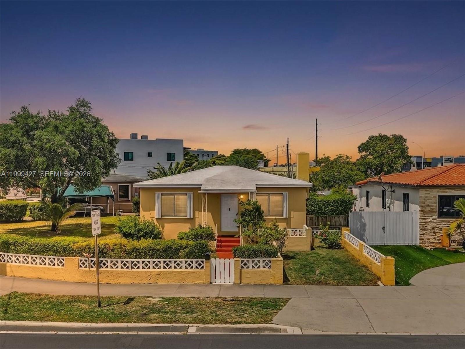 A single-story yellow house with a white fence and red steps at sunset — 10 SW 72nd Ave, Miami FL 33144, MIAMI, FL