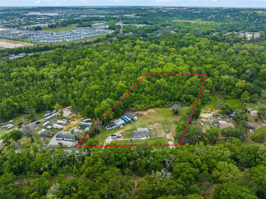 An aerial view shows a house and several outbuildings on a wooded lot — 16838 OLD HIGHWAY 50, WINTER GARDEN, FL