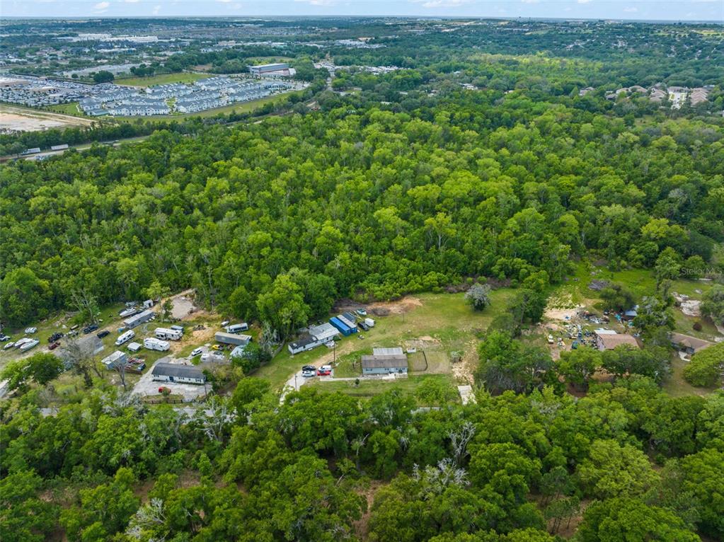 An aerial view shows a house and several outbuildings surrounded by a dense forest — 16838 OLD HIGHWAY 50, WINTER GARDEN, FL