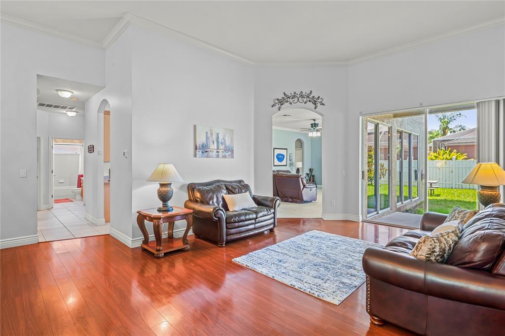A living room with hardwood floors, leather furniture, and sliding glass doors leading to a yard — 12801 STANWYCK CIRCLE, TAMPA, FL