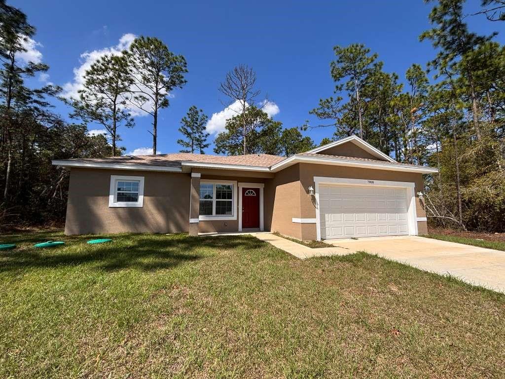 A single-story tan house with a red front door and an attached two-car garage — 7908 N GALENA AVENUE, DUNNELLON, FL
