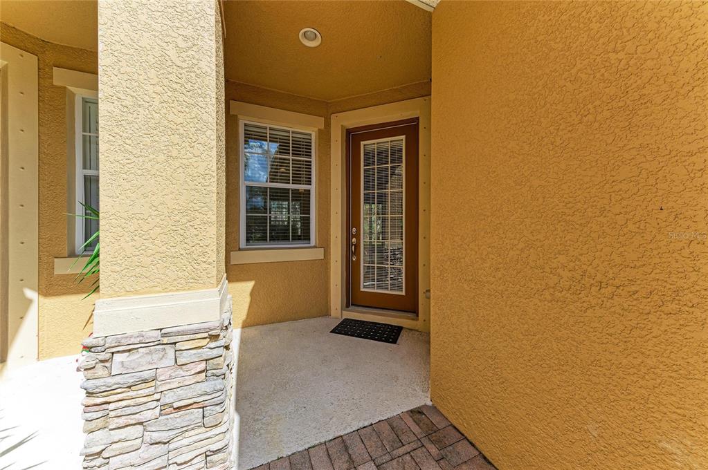 A covered entryway features a brown door with glass panels, a window, and stone accents — 8160 VILLA GRANDE CT, SARASOTA, FL