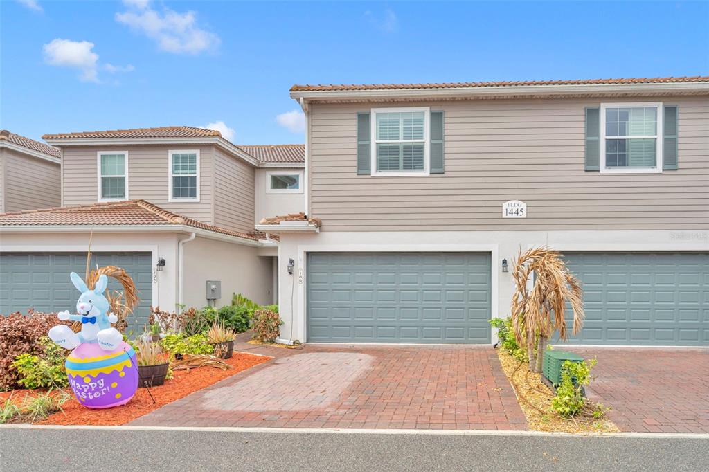 An exterior view of a two-story townhouse with a brick driveway and a garage — 1445 ISABELLA DRIVE UNIT 105, MELBOURNE, FL