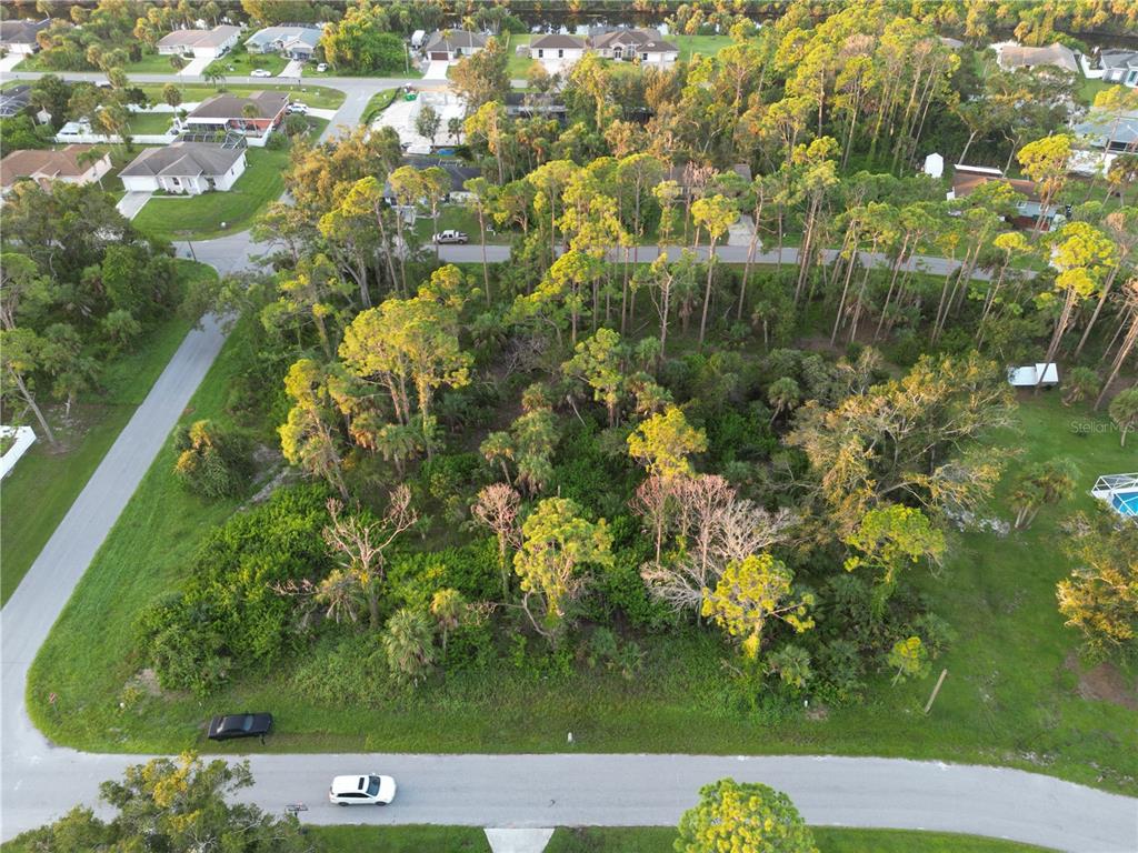 An aerial view shows a wooded, undeveloped residential lot surrounded by houses and streets — YUMA AVENUE, NORTH PORT, FL