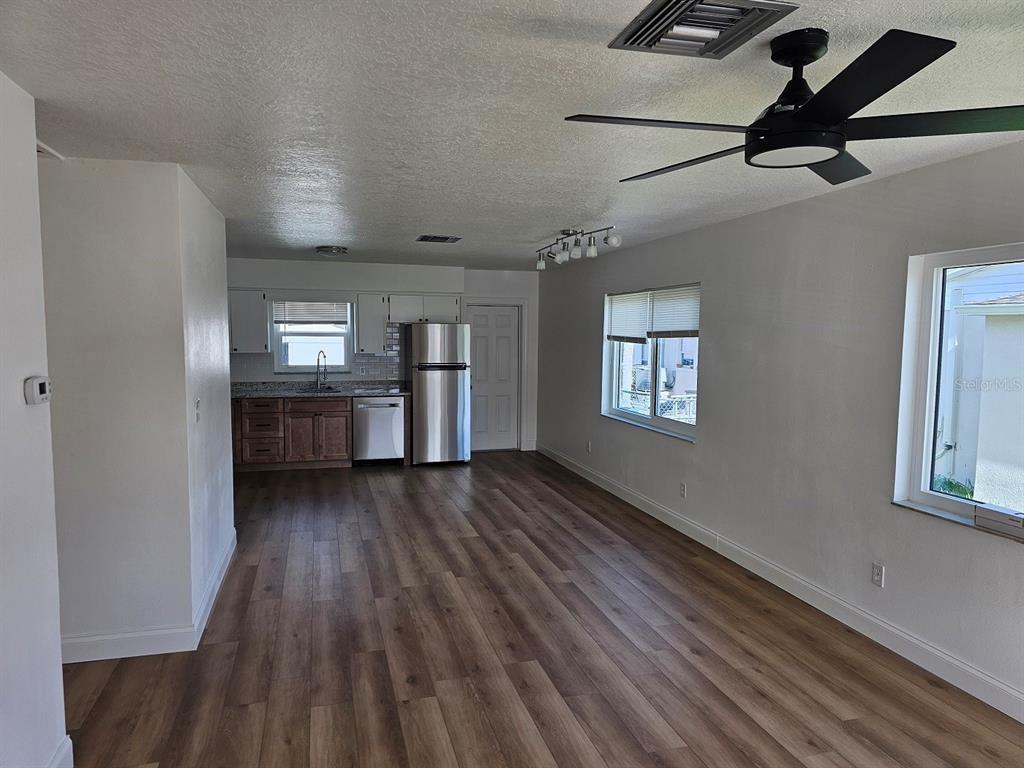 An open-concept kitchen and living area features wood-look flooring, stainless steel appliances, and white walls — 175 174TH TERRACE DRIVE E UNIT 2, REDINGTON SHORES, FL