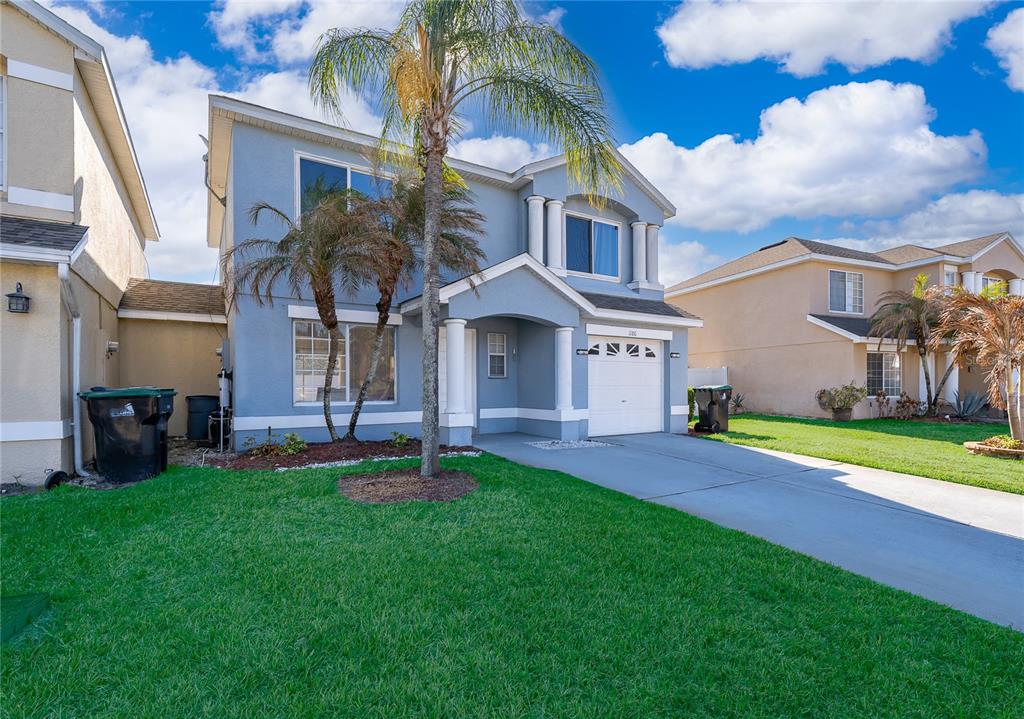 A two-story blue house with a palm tree, a driveway, and a garage — 1186 SANDESTIN WAY, ORLANDO, FL