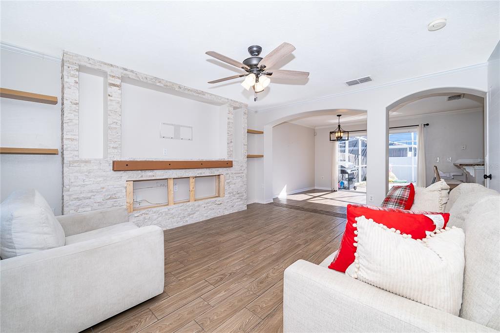 A living room features a stone-accented media wall, wood-look tile flooring, and an arched entryway — 1186 SANDESTIN WAY, ORLANDO, FL