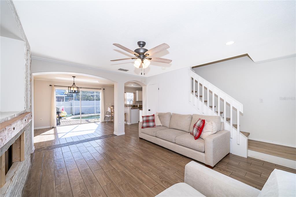A living room with wood-look tile floors, a beige sofa, and a staircase — 1186 SANDESTIN WAY, ORLANDO, FL