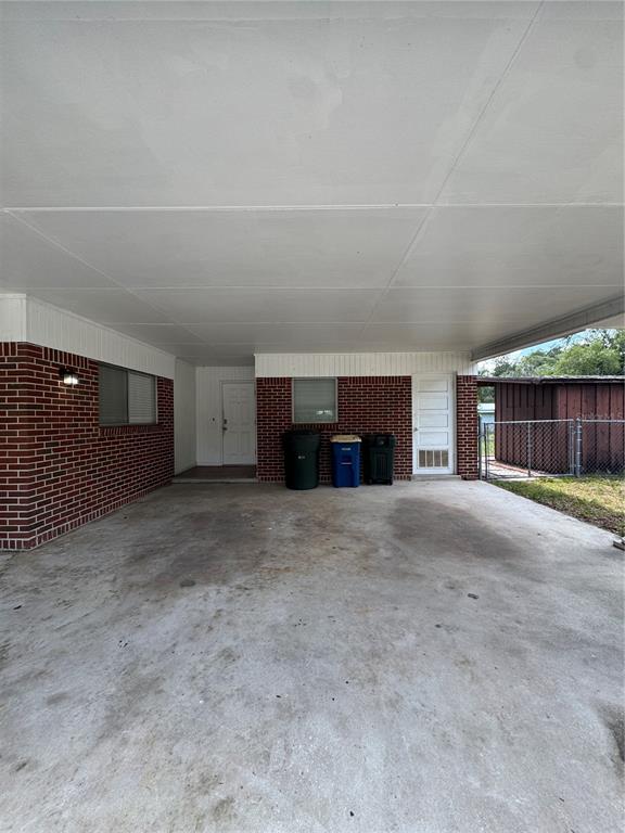 A concrete carport features a brick exterior wall, a white ceiling, and three trash bins — 2255 E HELEN CIRCLE, BARTOW, FL