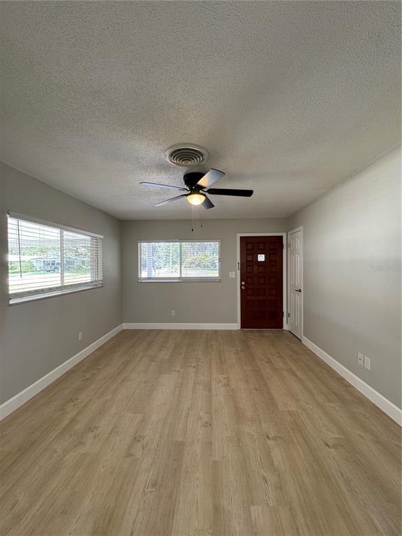 An empty room features light wood-look flooring, gray walls, a ceiling fan, and a front door — 2255 E HELEN CIRCLE, BARTOW, FL