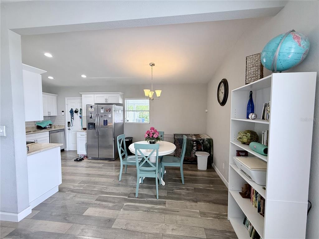 A kitchen and dining area with light wood-look flooring, white cabinets, and a round table — 4497 MENHADEN DRIVE SE, ST PETERSBURG, FL