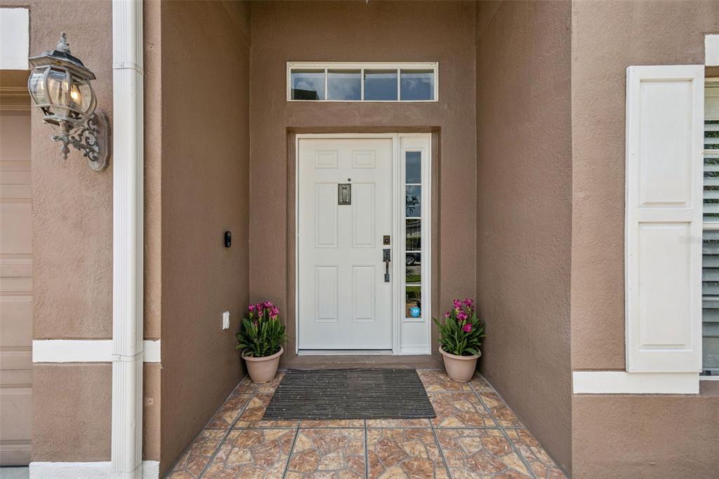 A white front door with a side window and transom sits under a covered entryway — 14580 SAINT GEORGES HILL DRIVE, ORLANDO, FL