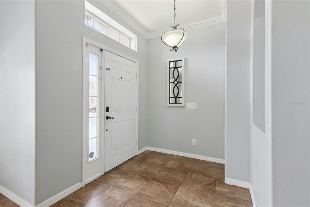 A bright entryway features a white front door, tile flooring, and a hanging light fixture — 14580 SAINT GEORGES HILL DRIVE, ORLANDO, FL