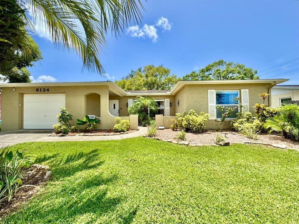 A single-story house with a tan stucco exterior, a one-car garage, and a front lawn — 8134 WINTHROP DRIVE, PORT RICHEY, FL