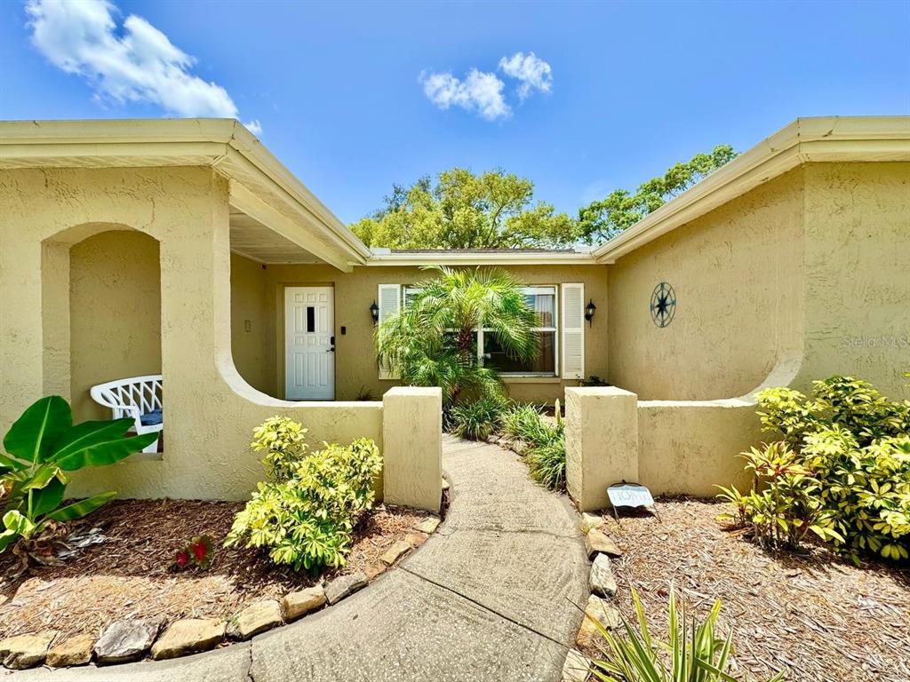 A walkway leads to the front entrance of a house with a stucco exterior — 8134 WINTHROP DRIVE, PORT RICHEY, FL