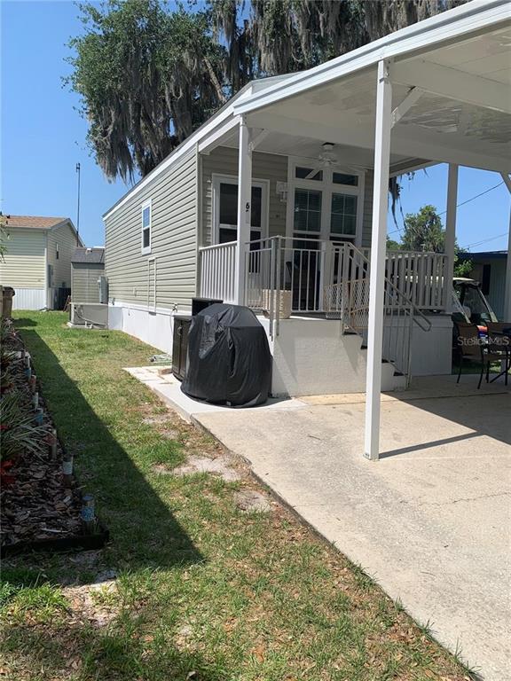 A mobile home exterior features a covered carport, a small front porch, and a grill — 699 CINDI AVENUE, LEESBURG, FL