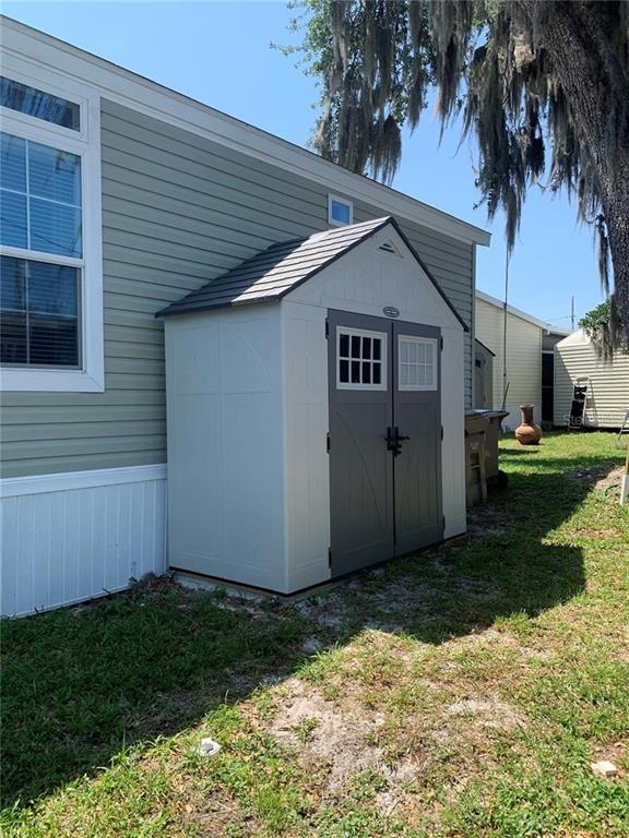 A light-colored plastic storage shed is attached to the side of a mobile home — 699 CINDI AVENUE, LEESBURG, FL