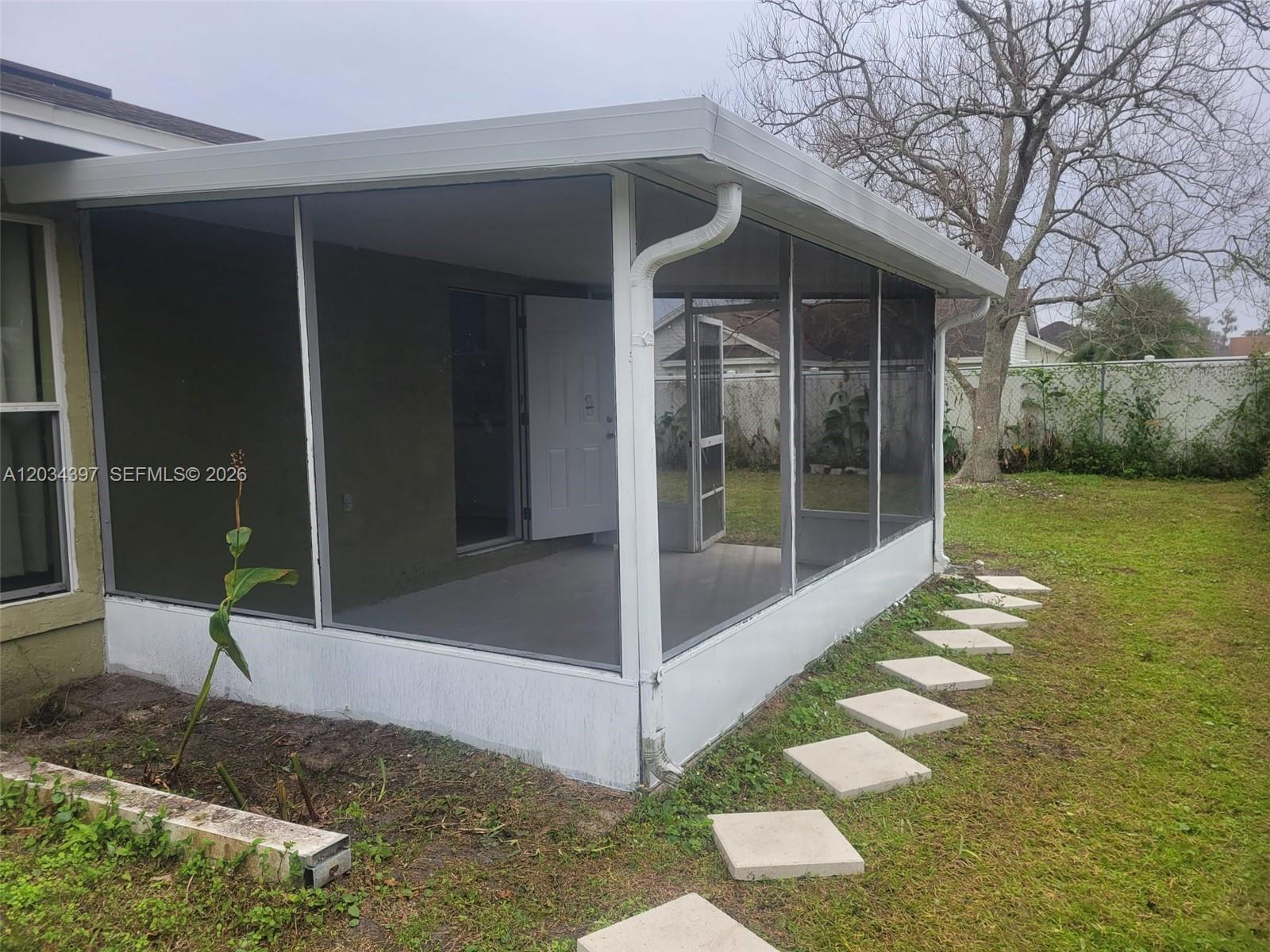 A screened-in patio with a white frame and concrete floor sits in a grassy backyard — 20420 Marlin st # B, Orlando FL 32833, ORLANDO, FL