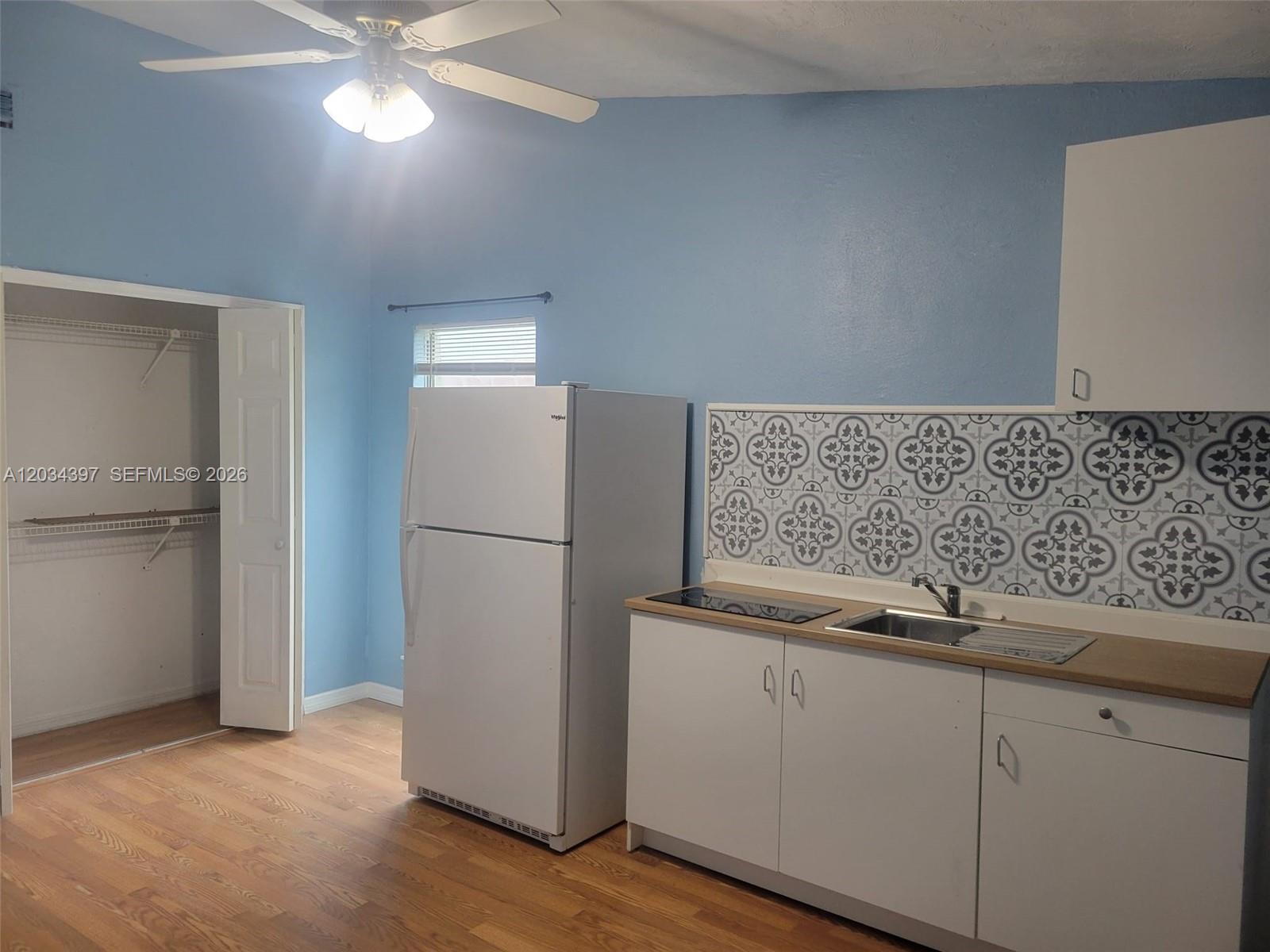 A kitchen features blue walls, white cabinets, a white refrigerator, and a patterned tile backsplash — 20420 Marlin st # B, Orlando FL 32833, ORLANDO, FL