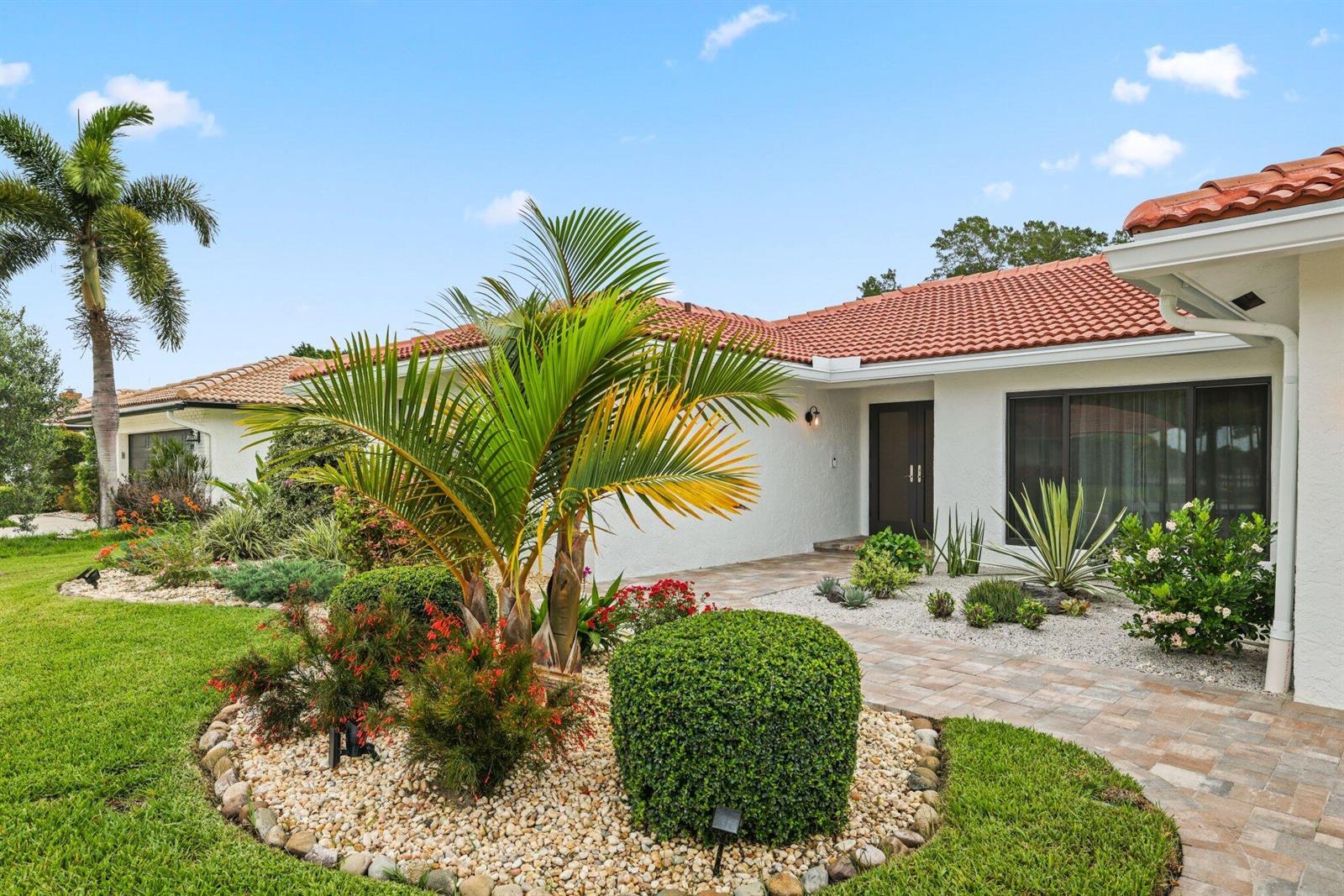 A white house with a red tile roof features a landscaped front yard and walkway — 20195 Back 9 Drive, Boca Raton FL 33498, BOCA RATON, FL