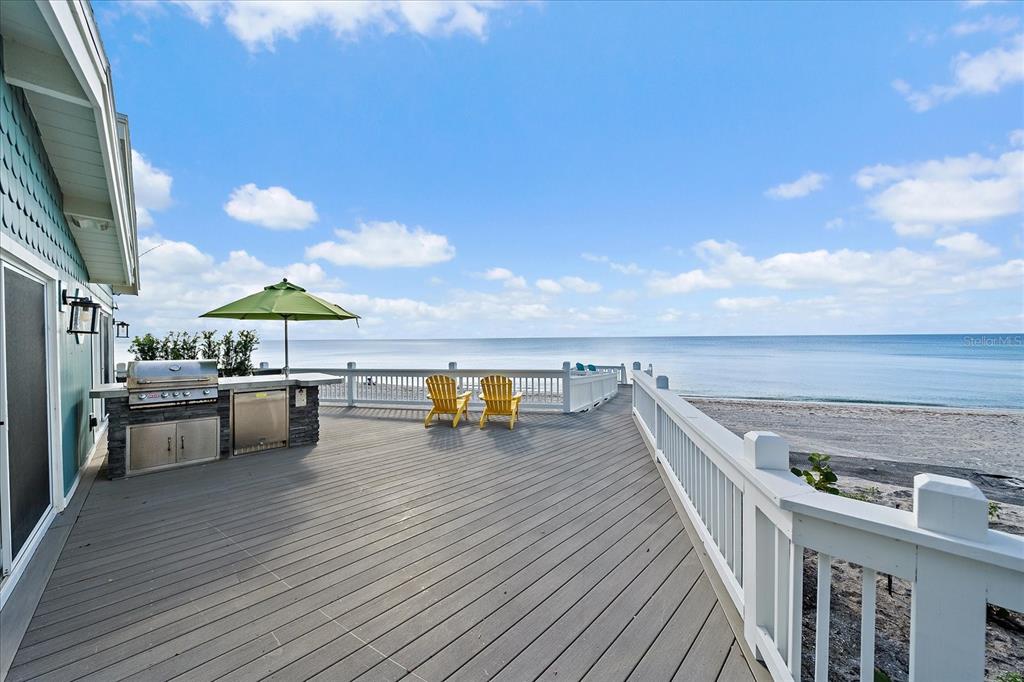 A wooden deck with an outdoor kitchen and yellow chairs overlooks the ocean — 7570 MANASOTA KEY ROAD, ENGLEWOOD, FL