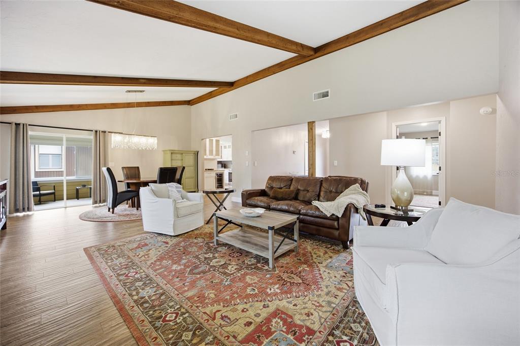 A living room with vaulted ceilings, exposed beams, a leather sofa, and a patterned rug — 8080 NW 47TH STREET, OCALA, FL