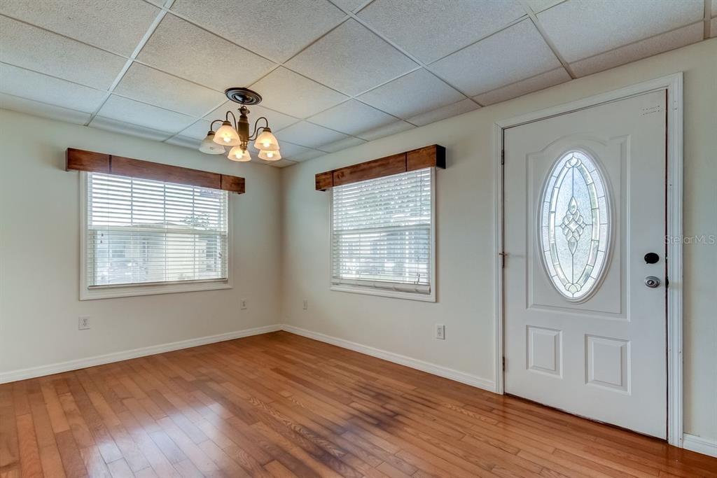 A room with wood flooring, a drop ceiling, two windows with valances, and an entry door — 278 PELICAN DRIVE N, OLDSMAR, FL