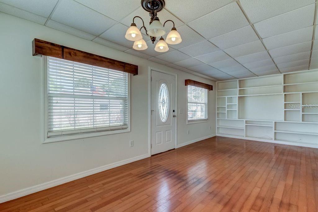 A room with wood flooring, a drop ceiling, a chandelier, windows, and built-in shelving — 278 PELICAN DRIVE N, OLDSMAR, FL