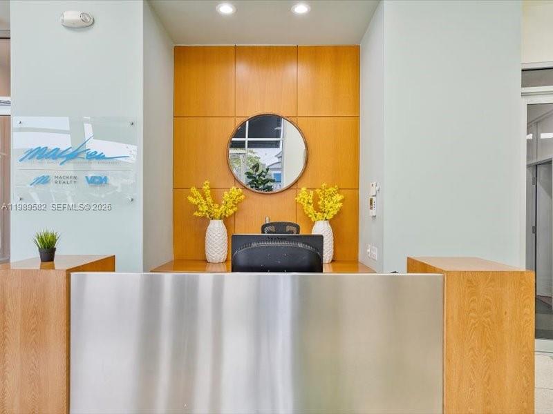 A reception desk with a metal front sits before a wood-paneled wall and mirror — 2404 Hollywood Blvd, Hollywood FL 33020, HOLLYWOOD, FL