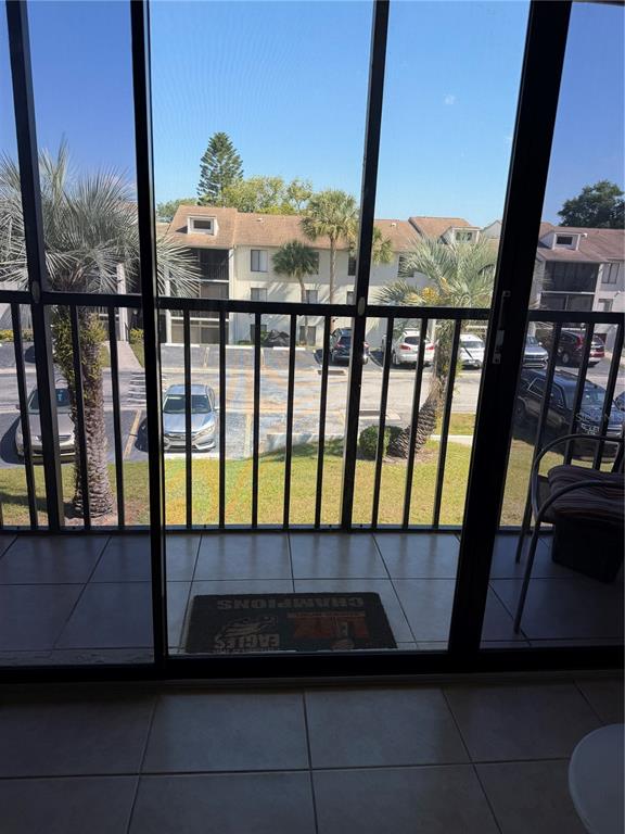 A view from a tiled balcony through a screen door looking out at a parking lot — 2688 PINE RIDGE WAY N UNIT A2, PALM HARBOR, FL