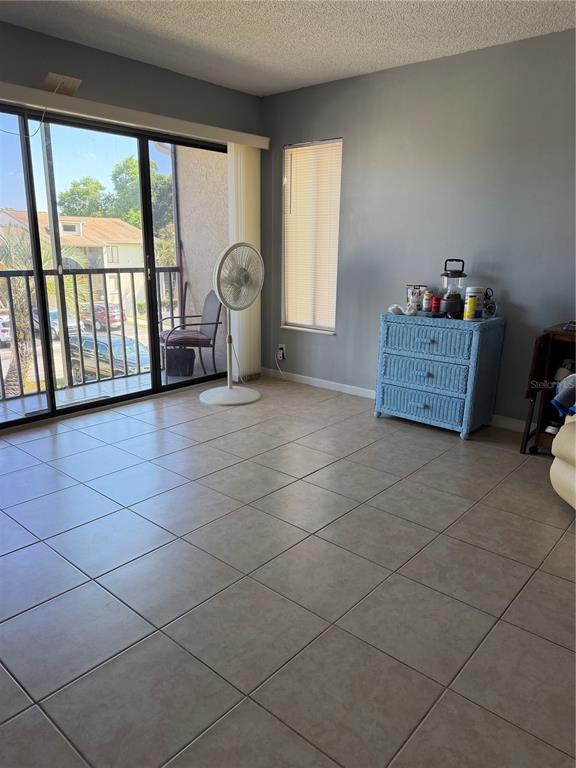 A living room features light tile flooring, a sliding glass door to a balcony, and a dresser — 2688 PINE RIDGE WAY N UNIT A2, PALM HARBOR, FL