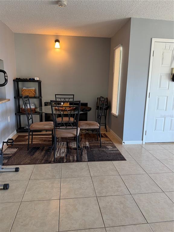 A dining area features a glass table, four chairs, a rug, and a black shelving unit — 2688 PINE RIDGE WAY N UNIT A2, PALM HARBOR, FL