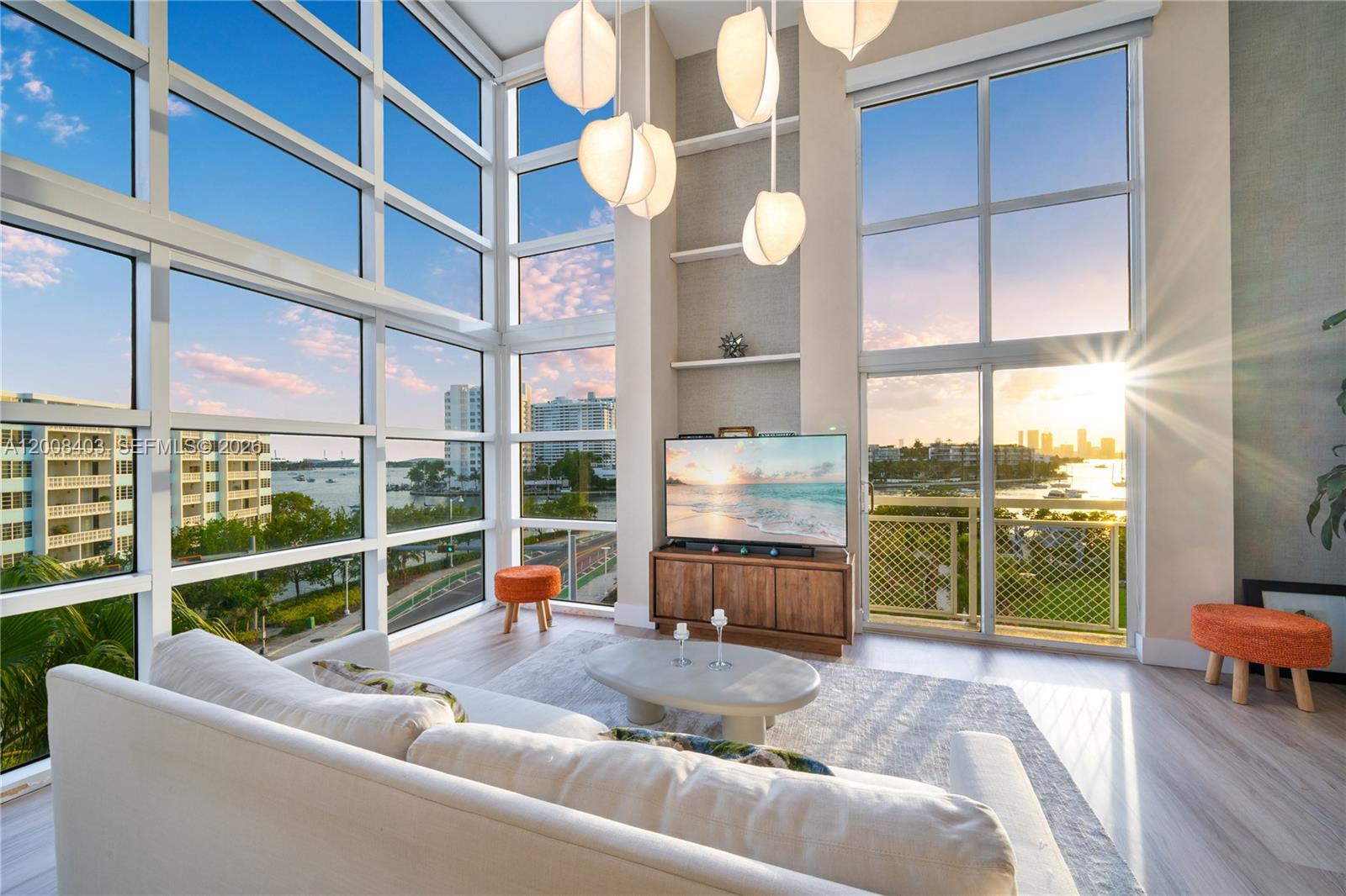 A modern living room features floor-to-ceiling windows, a white sofa, and a pendant light fixture — 1701 Sunset Harbour Dr # L501, Miami Beach FL 33139, MIAMI BEACH, FL