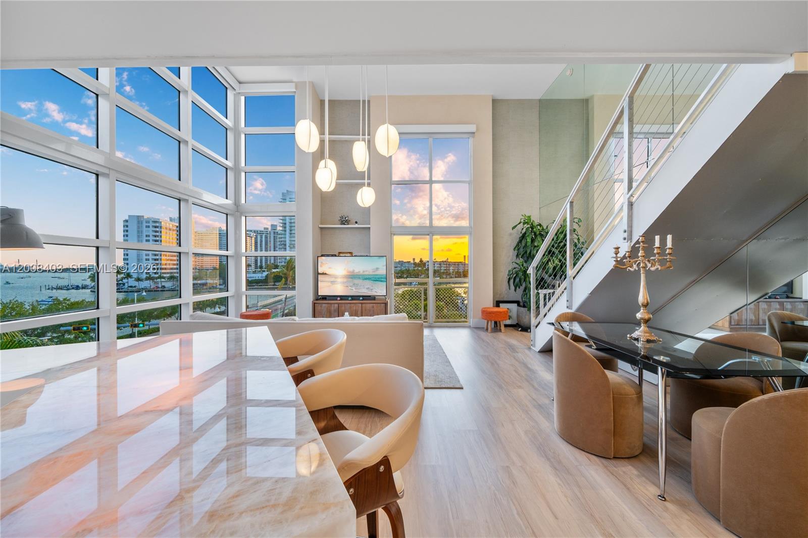 A modern living and dining area features floor-to-ceiling windows, a staircase, and waterfront views — 1701 Sunset Harbour Dr # L501, Miami Beach FL 33139, MIAMI BEACH, FL