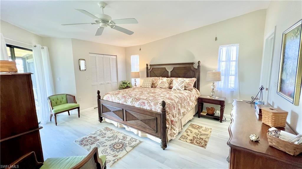 A bedroom features a large wooden bed, light-colored flooring, and a ceiling fan — 1640 ATARES DRIVE UNIT 31, PUNTA GORDA, FL