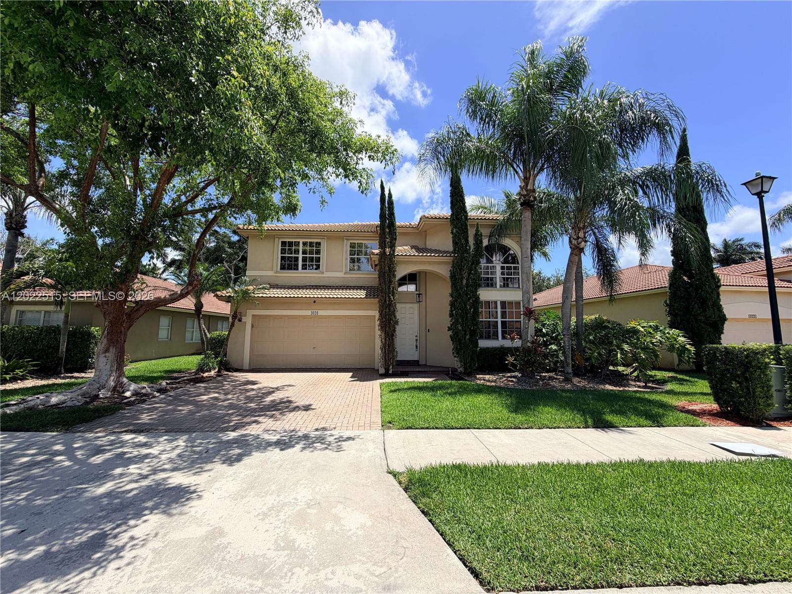 A two-story suburban house with a beige stucco exterior, tiled roof, and a paved driveway — 4020 Sapphire Cv, Weston FL 33331, WESTON, FL