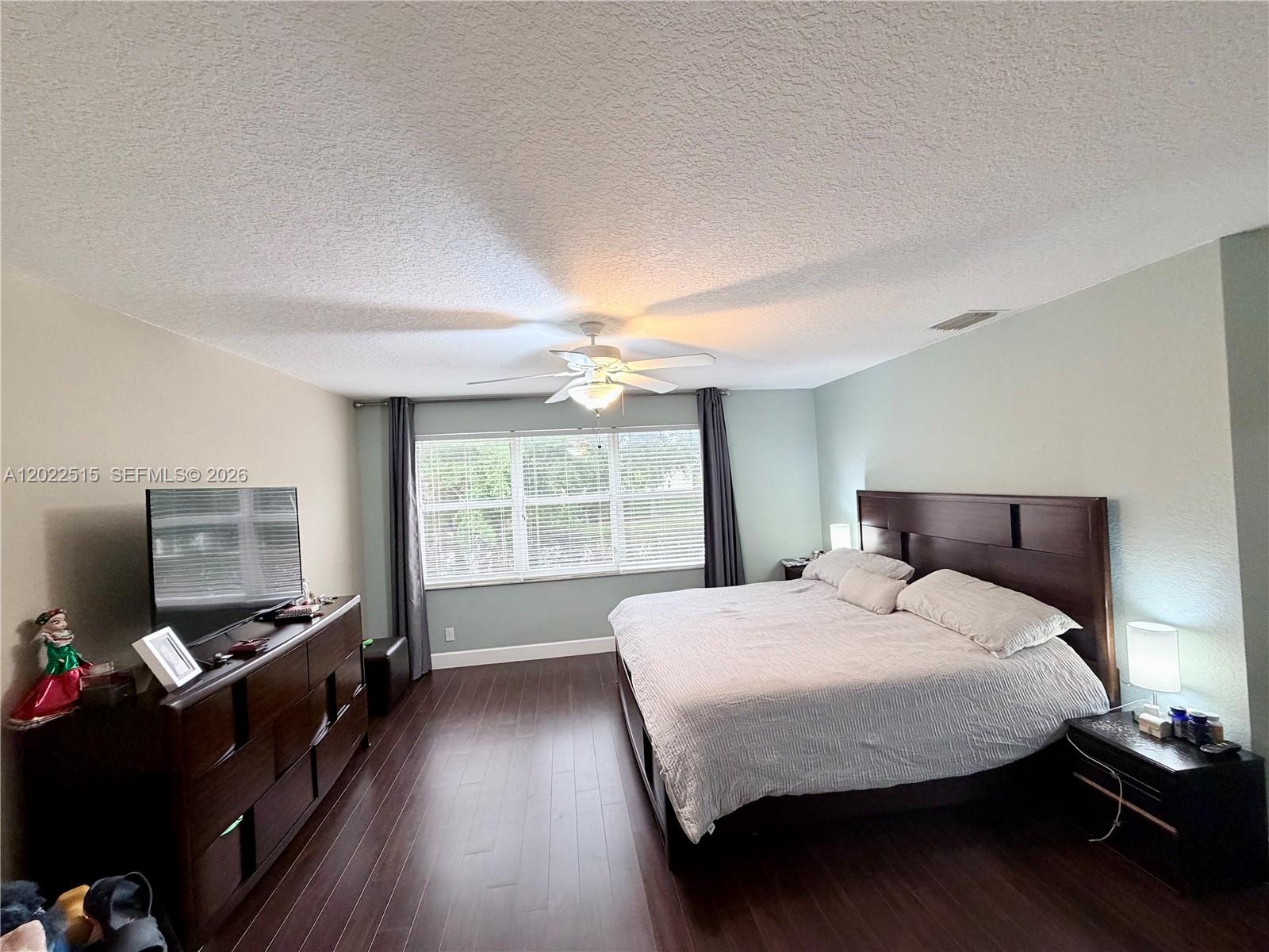 A bedroom features a dark wood bed frame, matching dresser, and dark hardwood flooring — 4020 Sapphire Cv, Weston FL 33331, WESTON, FL