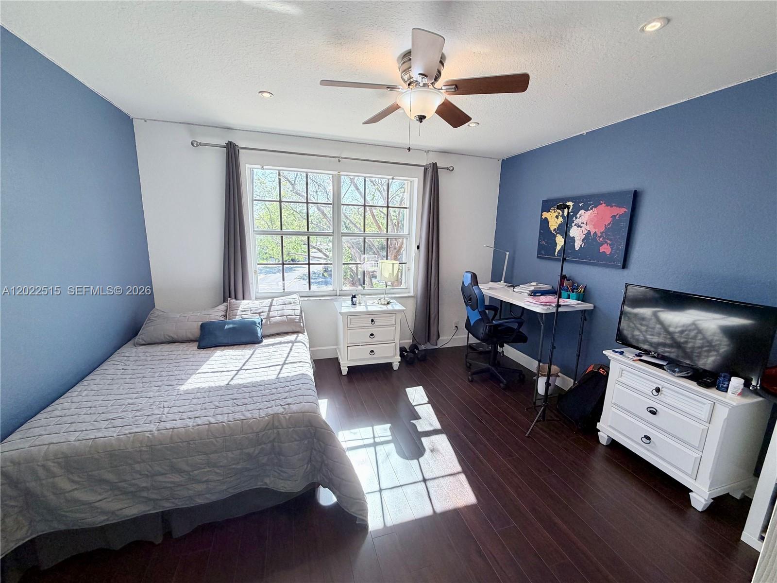 A bedroom features a bed, a desk with a chair, and a dresser on dark floors — 4020 Sapphire Cv, Weston FL 33331, WESTON, FL