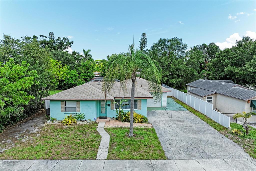 A light blue single-story house features a palm tree in the front yard and driveway — 2508 14TH AVENUE W, BRADENTON, FL