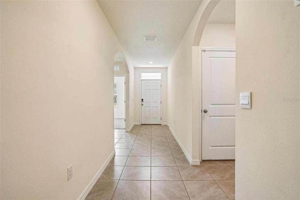 A tiled hallway leads to a white front door with a side door on the right — 134 HICKORY COURSE TRAIL, OCALA, FL
