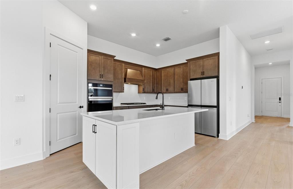 A modern kitchen features white cabinetry, a central island, and dark wood upper cabinets — 13531 CANYON RIDGE ROAD, SPRING HILL, FL