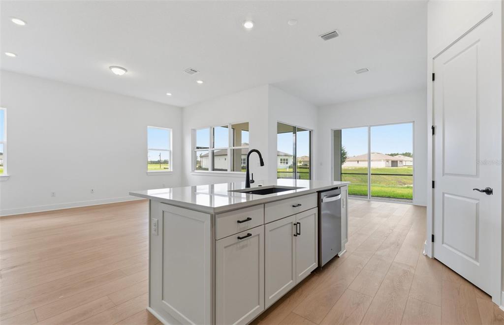 A modern kitchen island with a sink and dishwasher sits in a bright, open-concept room — 13531 CANYON RIDGE ROAD, SPRING HILL, FL