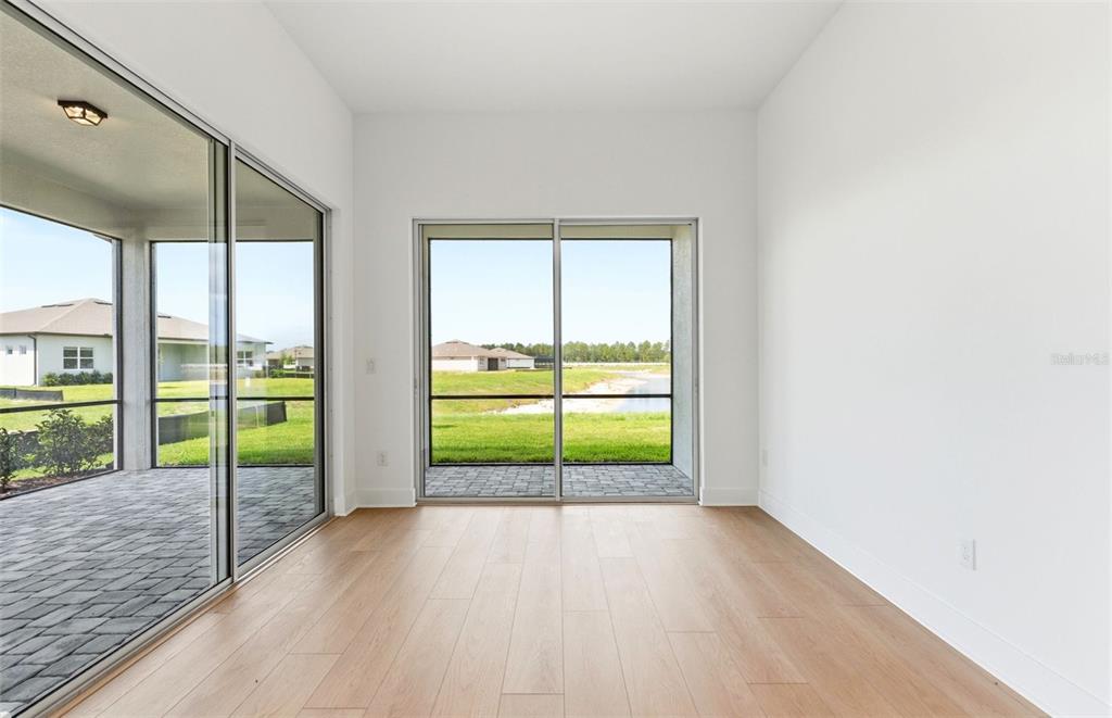 A bright room with light wood flooring and sliding glass doors leading to a patio — 13531 CANYON RIDGE ROAD, SPRING HILL, FL